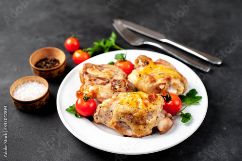 grilled chicken thighs on a white plate with spices on a stone background