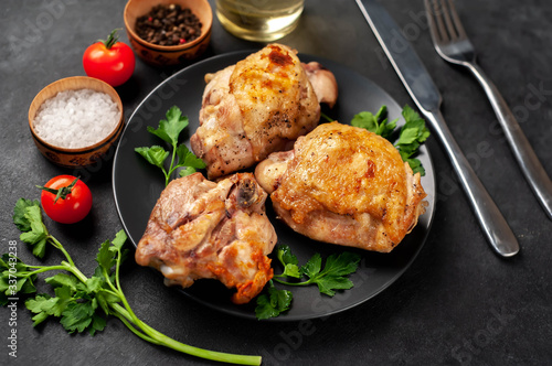 grilled chicken thighs on a black plate with spices on a stone background