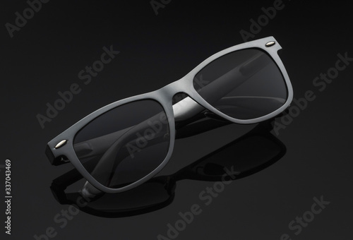 grey sunglasses on a gradient dark background with reflection