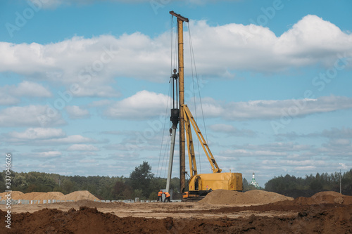 big yellow pile driver on a sunny day at a construction site with sand