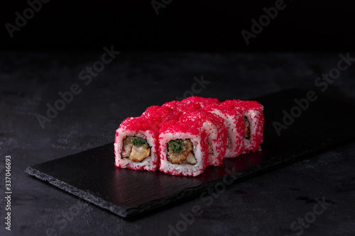 Traditional fresh japanese sushi rolls on a black stone California ebi . Roll ingredients:eel, cucumber, red tobik caviar, nori, rice. photo