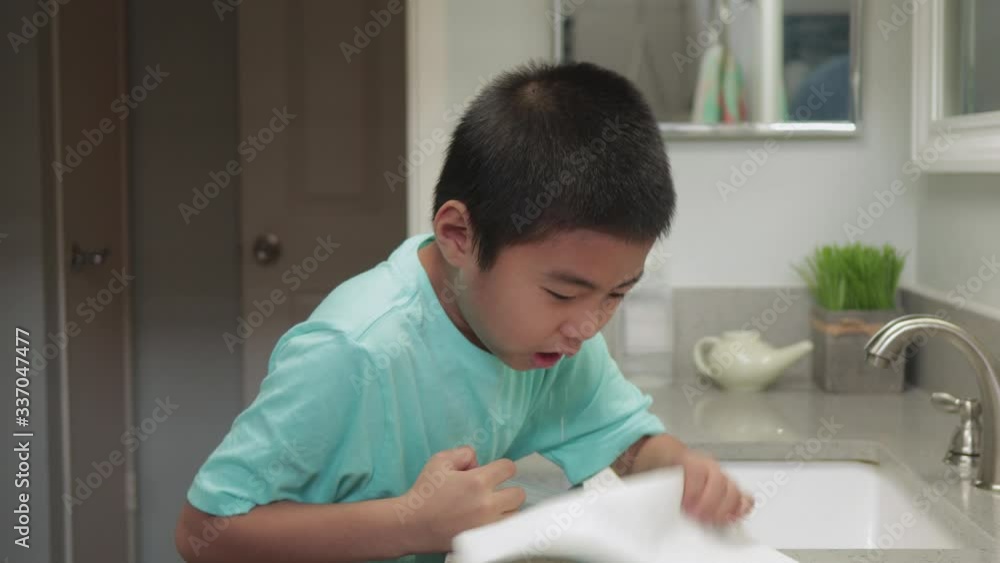 Young boy performing sinus nasal irrigation with saline and syringe at home in bathroom Young boy performing sinus nasal irrigation with saline and syringe at home in bathroom
