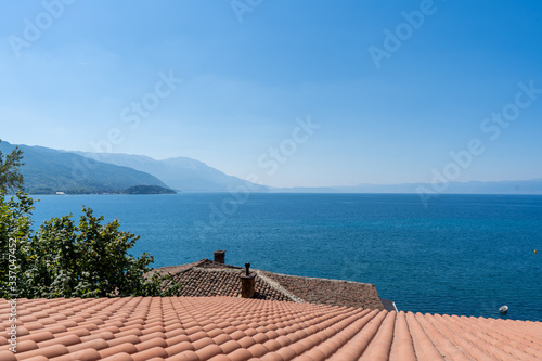 Beautiful view of red-tiled roof, green tree and Lake Ohrid, North Macedonia. August 2019 photo