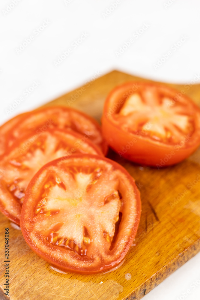 Sliced fresh tomato on the wooden cutting board with copy space Sliced fresh tomato on the wooden cutting board with copy space