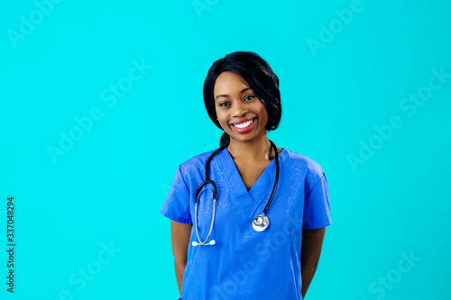Portrait of a smiling female doctor or nurse wearing blue scrubs uniform and stethoscope and looking to side, isolated on blue background