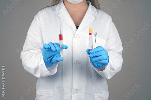 Fototapeta Naklejka Na Ścianę i Meble -  Doctor holding syringe in one hand and blood tube in the other