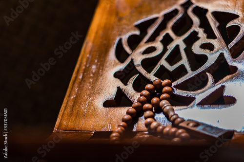 Islamic prayer beads or tasbih on rihal or quran book stand made from carved wood. It is suitable for background of Ramadan-themed design concepts or other Islamic religious events. photo