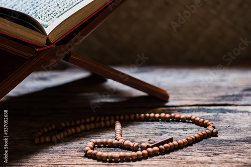 Tasbih or Islamic prayer beads with  Quran, the Holy Book of Muslims, on rehal or carved wood book rest.  photo