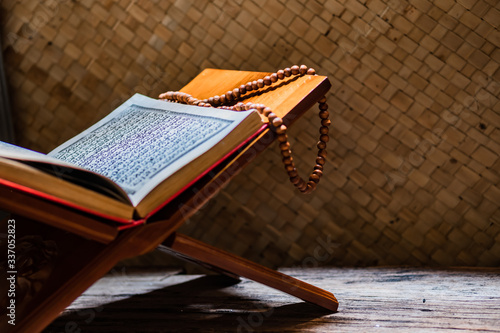 Tasbih or Islamic prayer beads on Quran, the Holy Book of Muslims, on rehal or carved wood book rest. Muslims will read more of this Scripture during Ramadan. photo