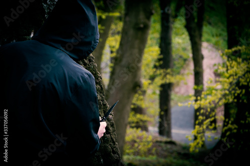 Mężczyzna z nożem schowany za drzewem