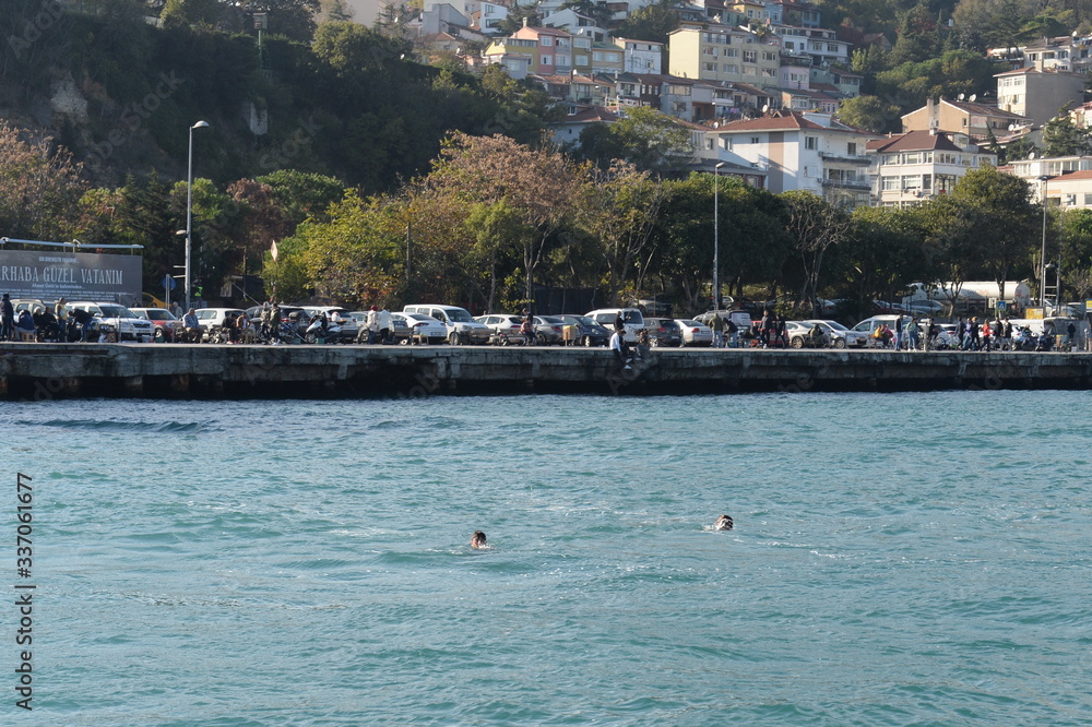 Obraz premium Men swim in the Bosphorus Strait near the embankment of Istanbul