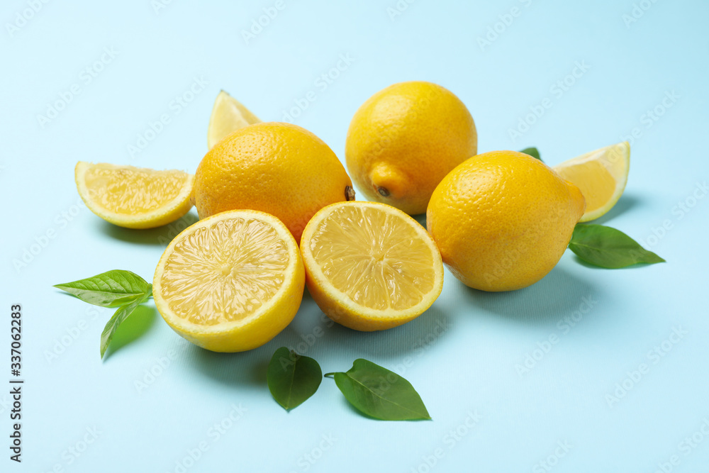 Fresh lemons with leaves on blue background, close up. Ripe fruit