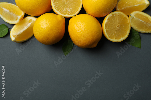 Fresh lemons with leaves on black background, top view. Ripe fruit
