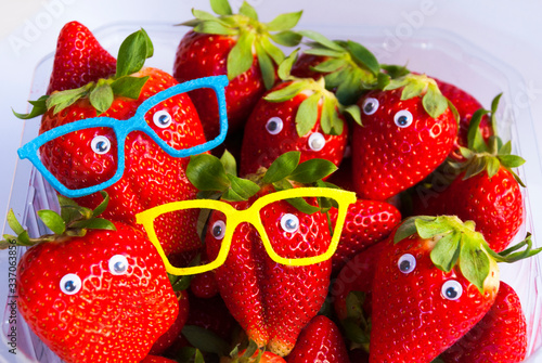 Creative food background. A lot of funny strawberries with faces and glases.