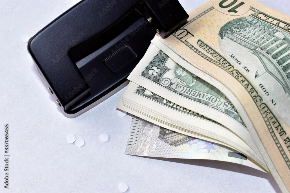 A clerical hole punch in the business with a hand a dollar and paper A clerical hole punch in the business with a hand a dollar and paper