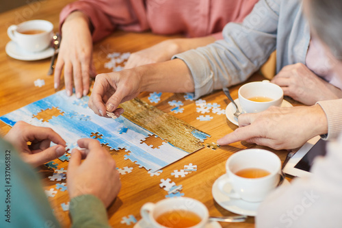 Close-up of family of four sitting at the table drinking tea and collecting puzzles together