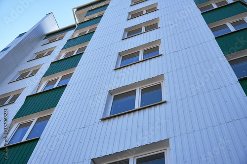 facade of a new multi-storey building with white and green metal siding  many Windows
