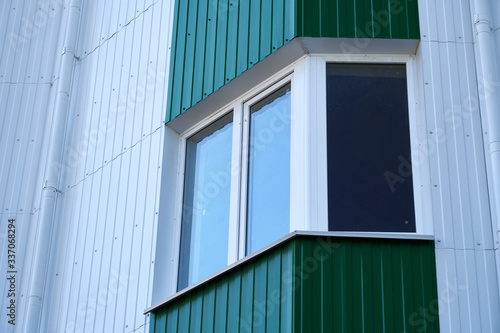 facade of a new multi-storey building with white and green metal siding, many Windows