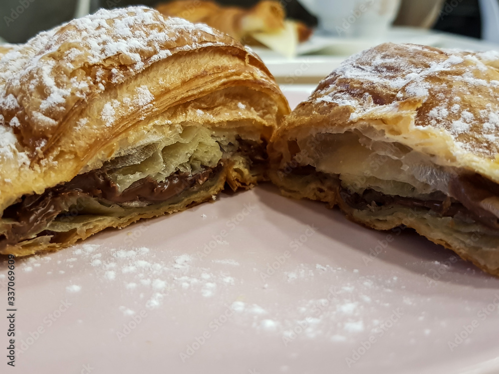 Delicious French croissant with chocolate filling and powdered sugar on top