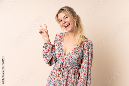 Blonde woman over isolated background smiling and showing victory sign