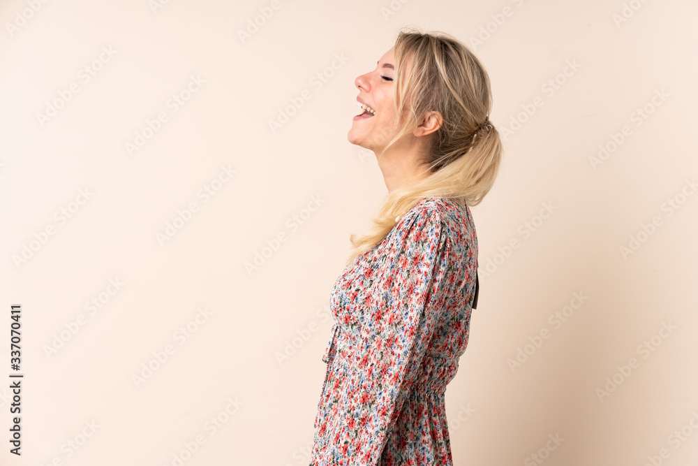 Blonde woman over isolated background laughing in lateral position Blonde woman over isolated background laughing in lateral position