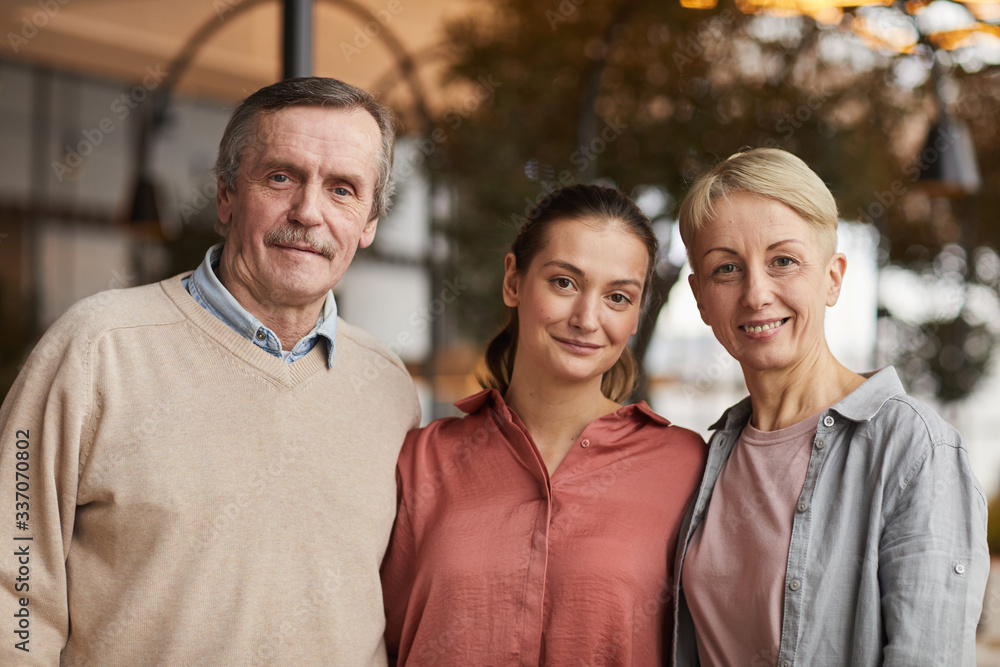 Portrait of two parents standing together with their daughter and smiling at camera Portrait of two parents standing together with their daughter and smiling at camera