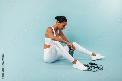 Quadro em tela Tired woman sitting on blue background in studio after training