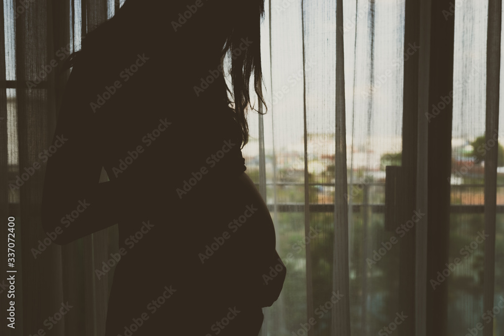 Slihouette of pregnant woman in the bedroom