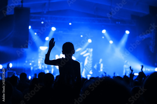 Obraz na płótnie silhouette of a girl in a concert crowd in front of the stage. fanaticism from a music group. banner for a concert festival w salonie