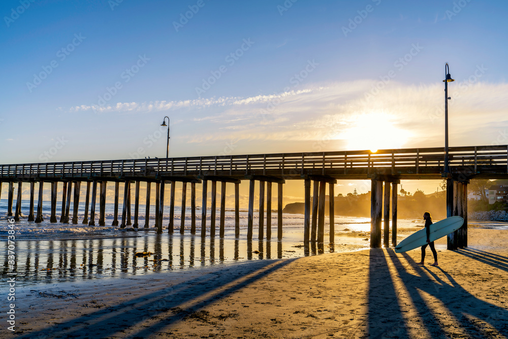Fototapeta premium Surfer Walking by Pier at Sunset 