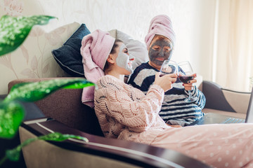 Mother's day. Mother and her adult daughter applied facial masks at home. Women chilling while having wine