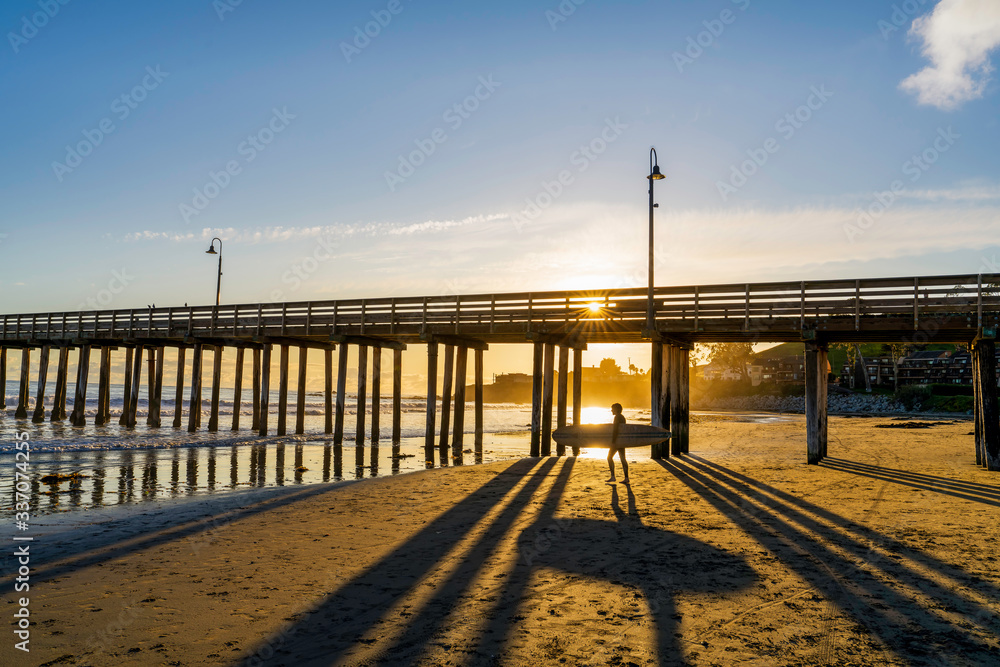 Fototapeta premium Silhouetted Surfer by Pier at Sunset 