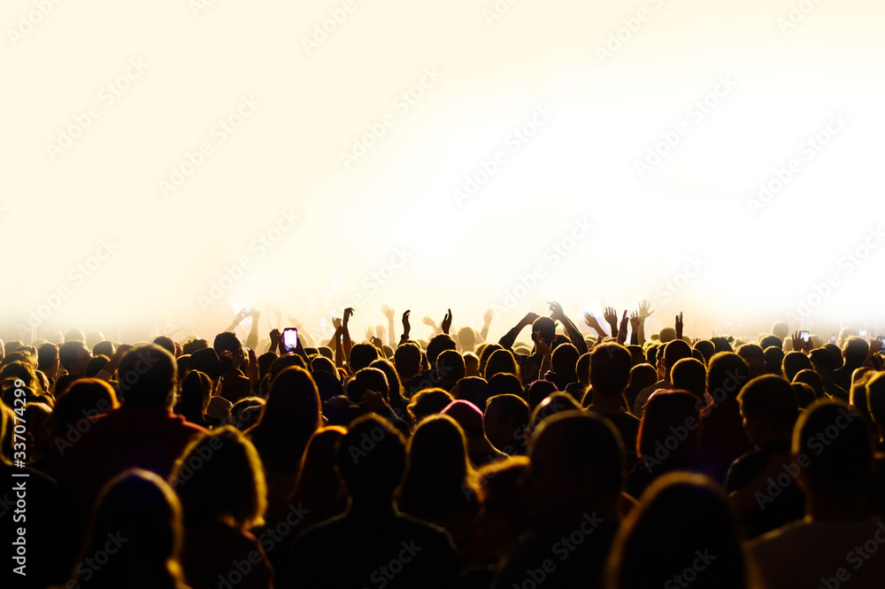 crowd with raised hands at a concert of a music festival. Silhouettes of people in front of a stage with an artist. night disco