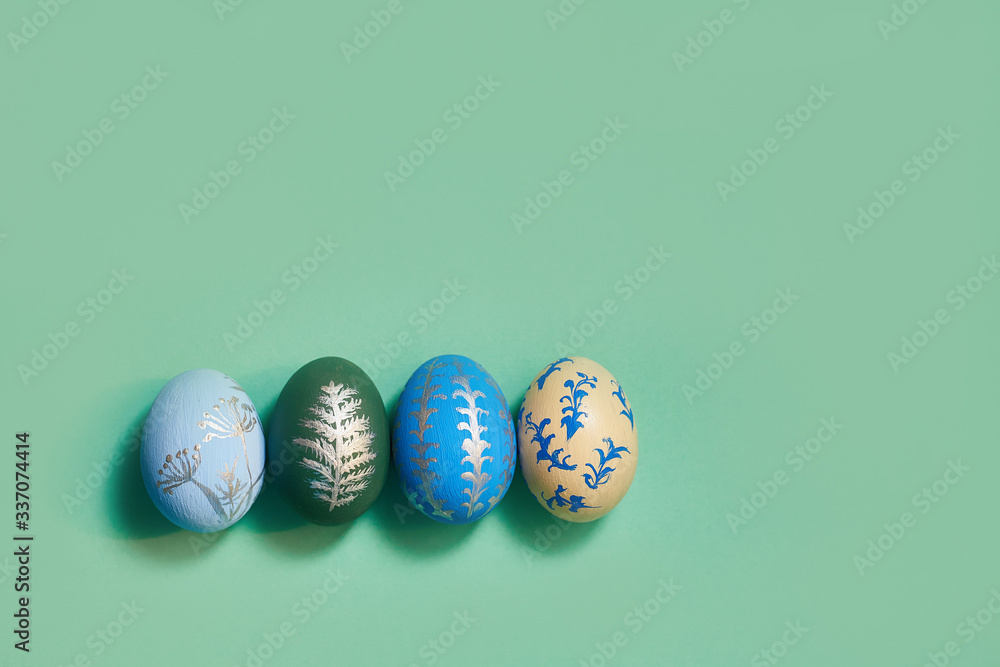 four colored easter eggs on a green background top view. copy space