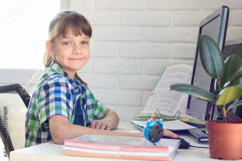 The girl does homework at the table, looked into the frame