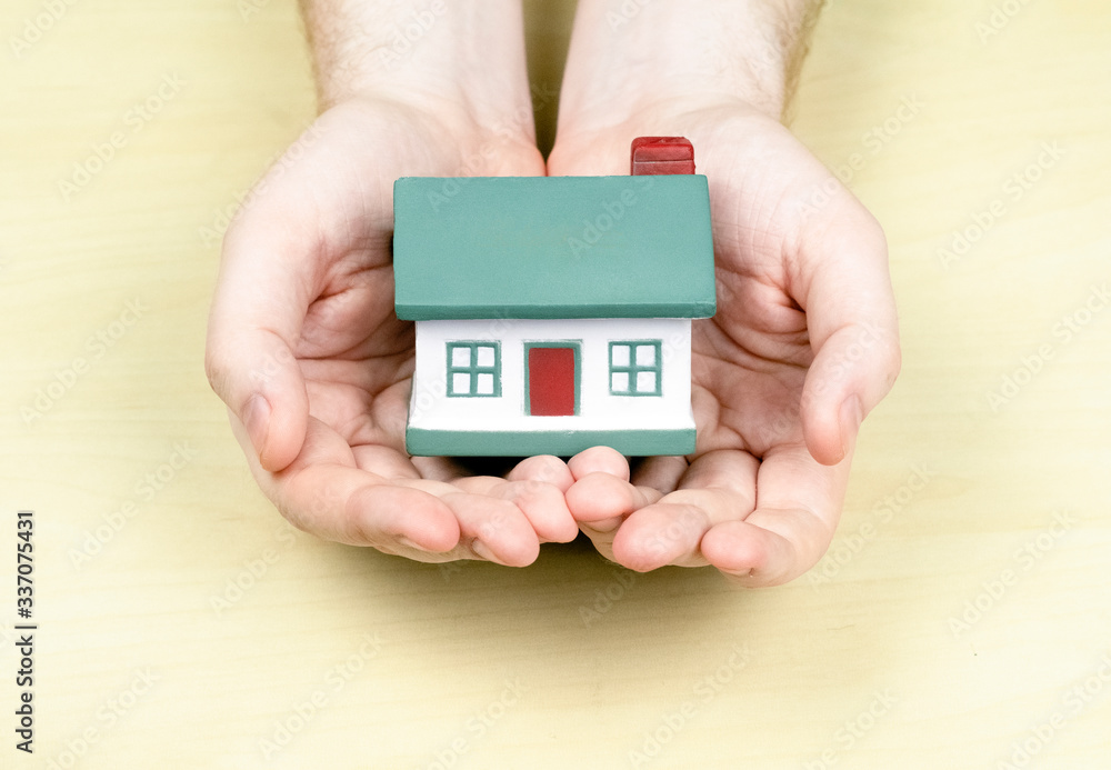 A small house with a red pipe in the hands of a man. Concept mortgage, purchase, sale, rental property. Happiness in his house, cottage
