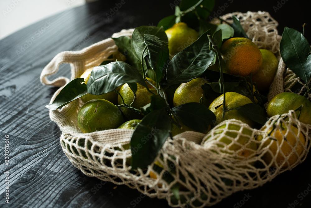 mesh bag with tangerines on a black wooden table