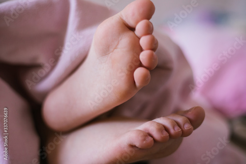 Children s feet. Foot. Feet under the blanket. Good morning. The child pulled his feet out from under the blanket.