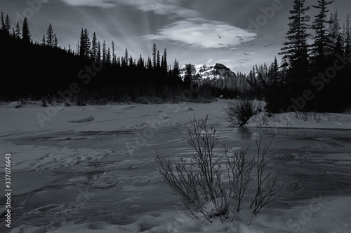 Sunset in winter in the mountains. Frozen Bighorn River by  Crescent Falls, Alberta, Canada. photo