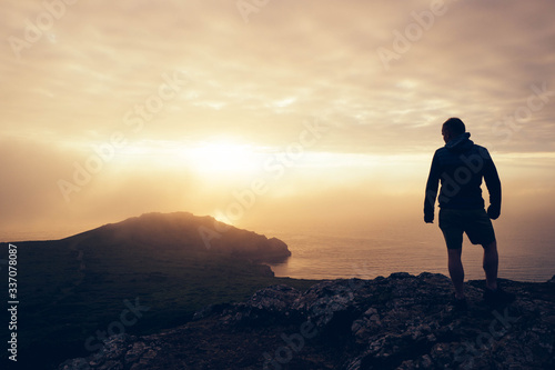 Man looking at misty ocean sunset photo