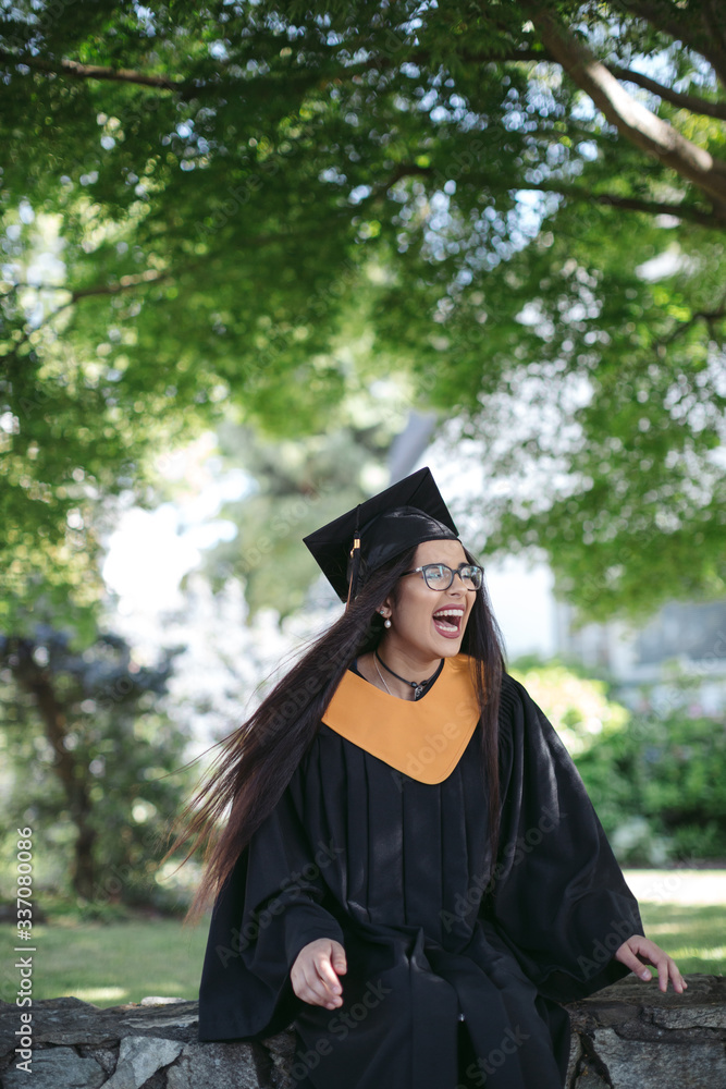 Teenage girl in cap and gown costume. Stock Photo Adobe Stock