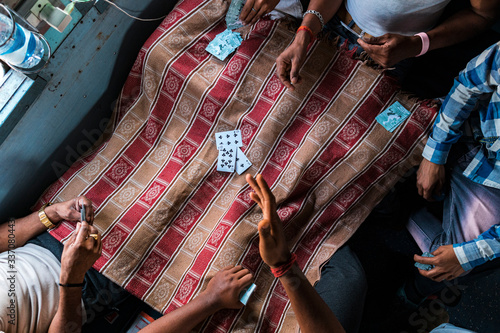 Crop people playing cards in train