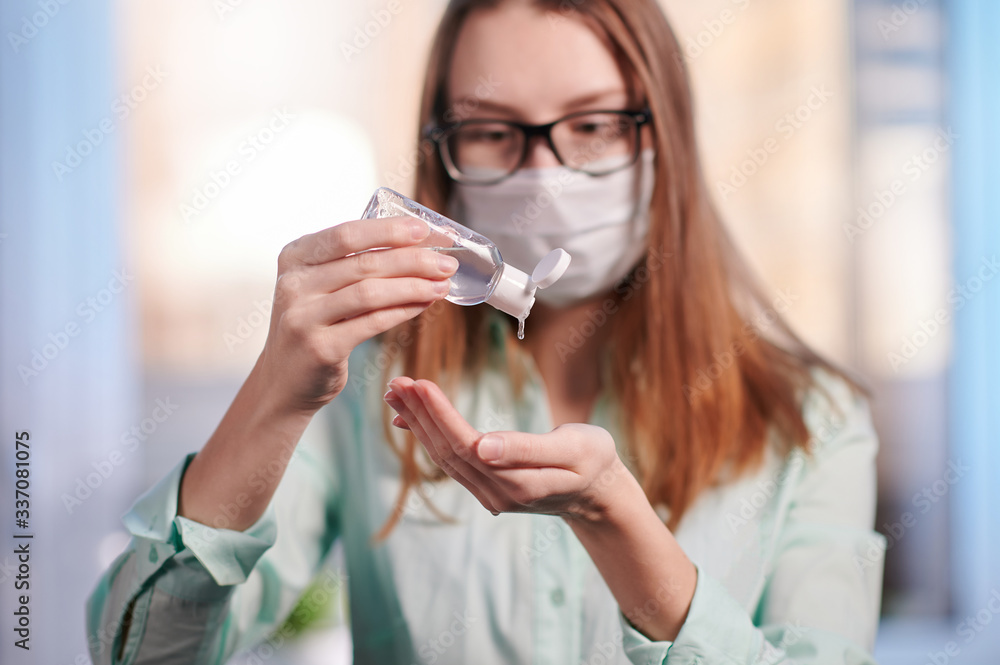 the girl in the mask with a disinfectant for hands closeup
