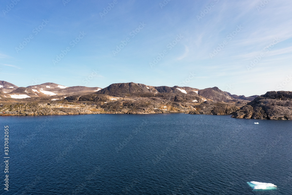 A small Greenlandic town can be seen in the distance, along with a few mountains.
