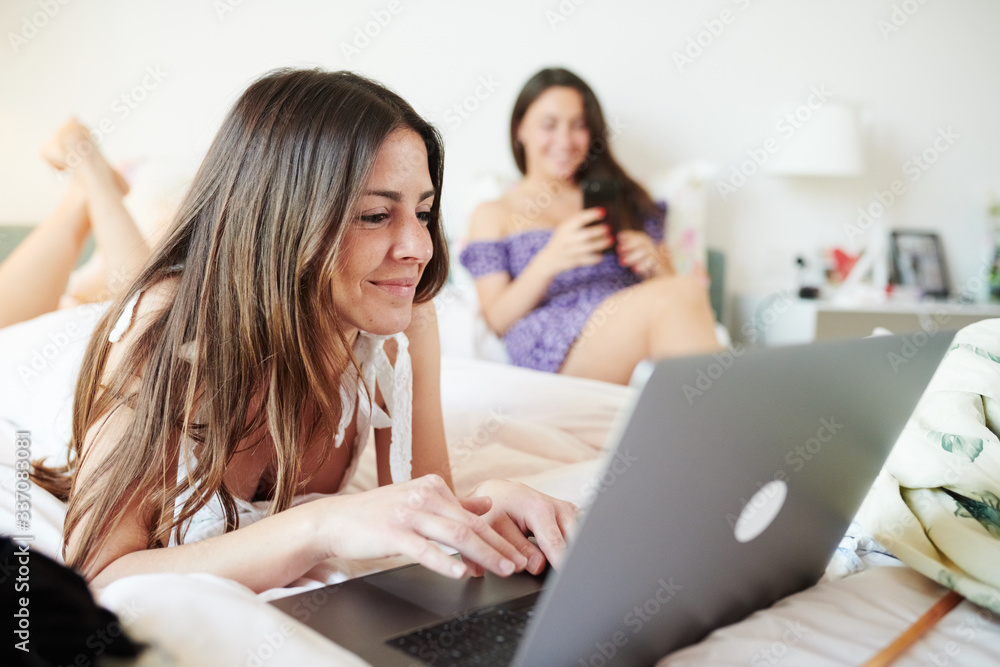 Chilling girlfriends lounging on bed at home Chilling girlfriends lounging on bed at home