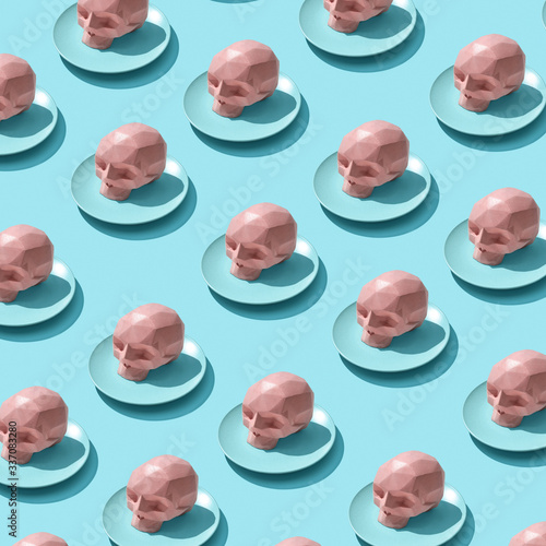 Plates with pink skulls as a pattern on a blue background with reflection of shadows.