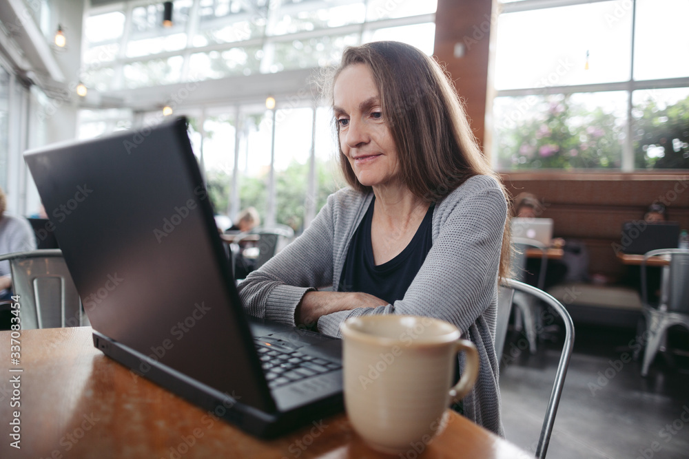Mature woman chatting on laptop at coffee shop. Mature woman chatting on laptop at coffee shop.