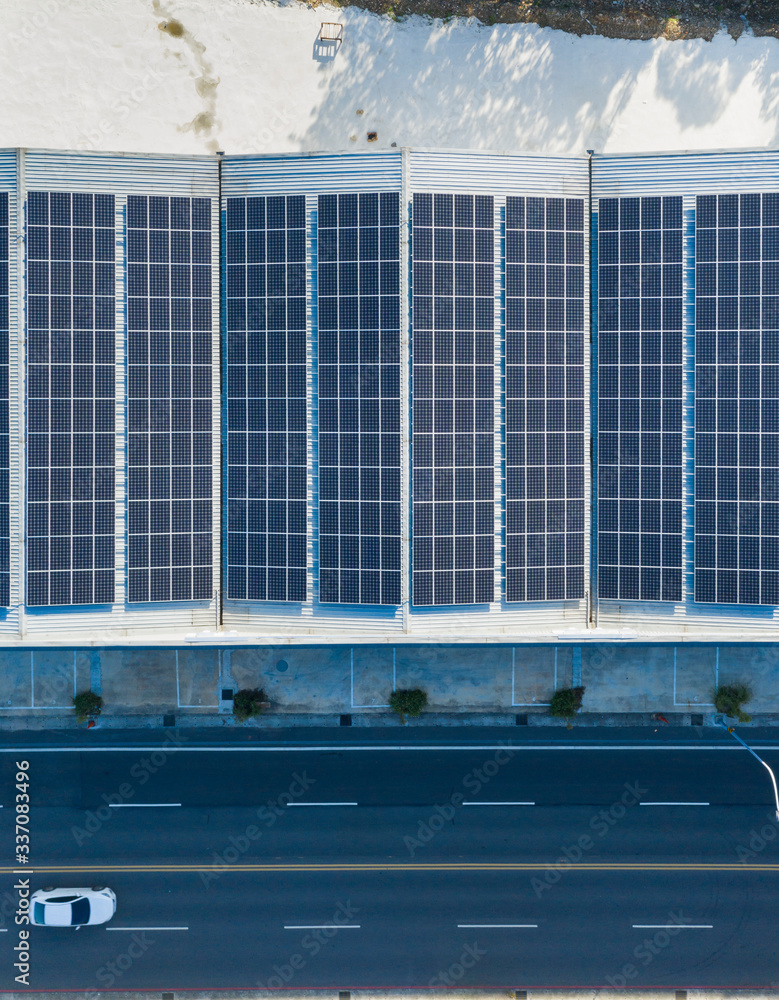 © Lawren Lu/Stocksy - Solar panels on the roof of factory on roadside