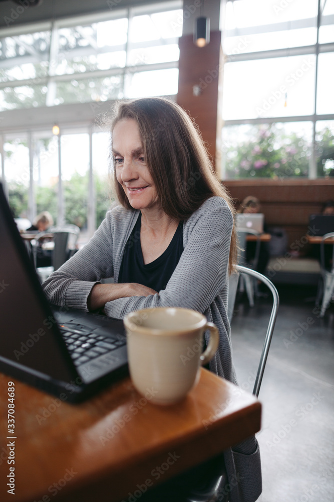 Mature woman chatting on laptop at coffee shop. Mature woman chatting on laptop at coffee shop.