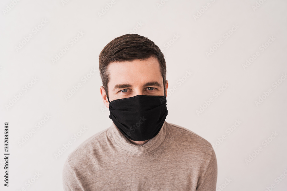 Young man in a black protective mask. Personal protective equipment for coronovirus. Homemade mask for access to public places. Young man in a black protective mask. Personal protective equipment for coronovirus. Homemade mask for access to public places.